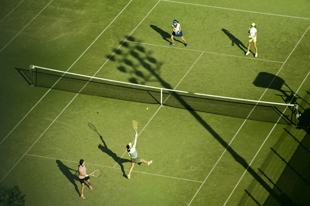 Tennis doubles match on a grass court, highlighting the sport's global popularity