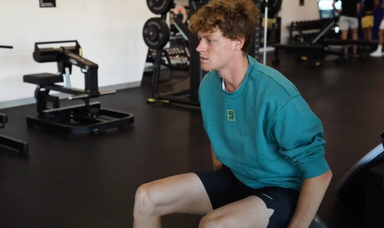Jannik Sinner working out in the gym, wearing a teal sweatshirt and black shorts